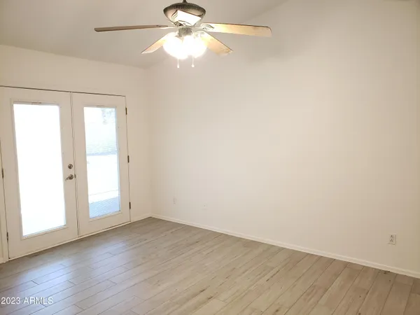 an empty room with wooden floor fan and windows