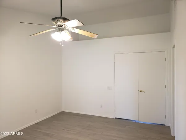 an empty room with a wooden floor and chandelier fan