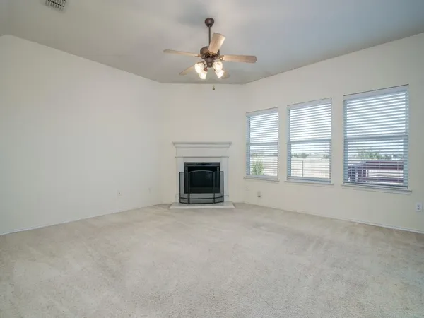an empty room with chandelier fan and windows