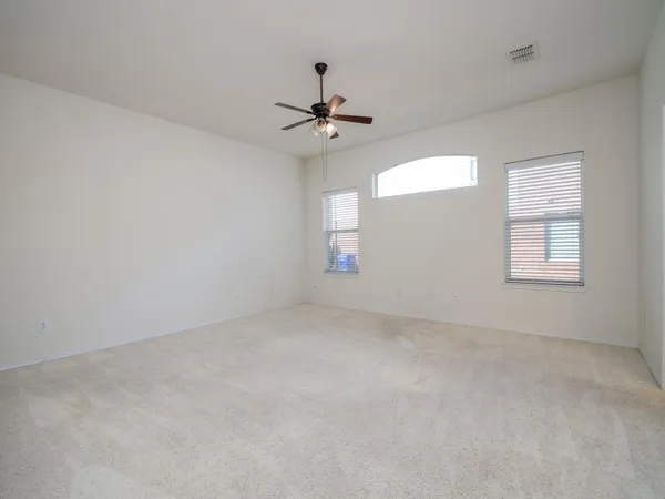 en empty room with windows and ceiling fan