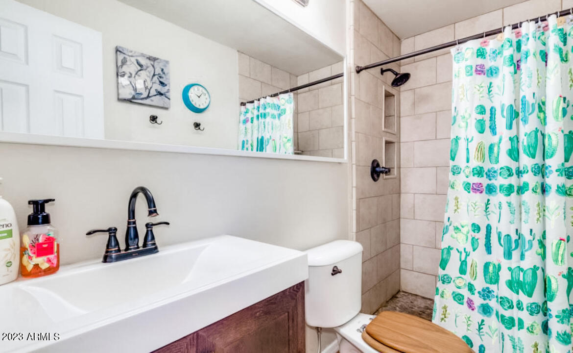 1430 East Meadowbrook Avenue Phoenix, AZ 85014 - Photo 8 of 18 a bathroom with a sink a toilet and a shower curtain