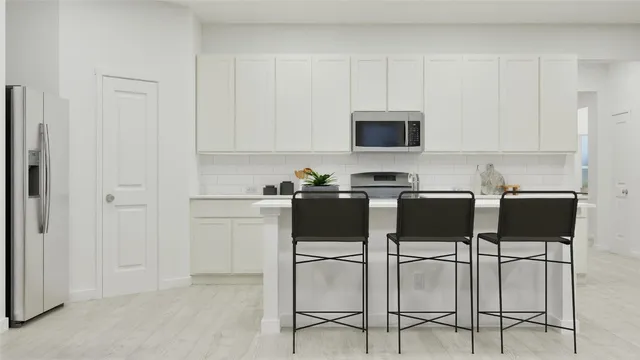 a kitchen with a sink white cabinets and stainless steel appliances