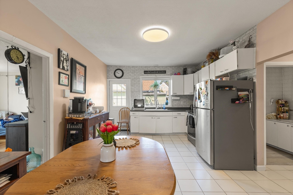 5 Washington Square Gloucester, MA 01930 - Photo 19 of 20 a kitchen with stainless steel appliances kitchen island granite countertop a refrigerator a stove top oven a dining table and chairs with wooden floor