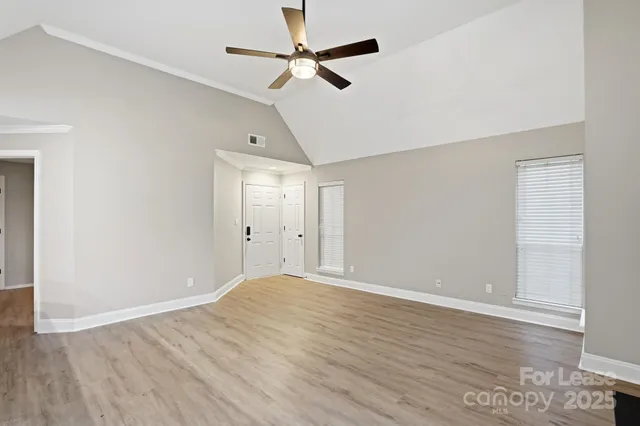 an empty room with wooden floor ceiling fan and window