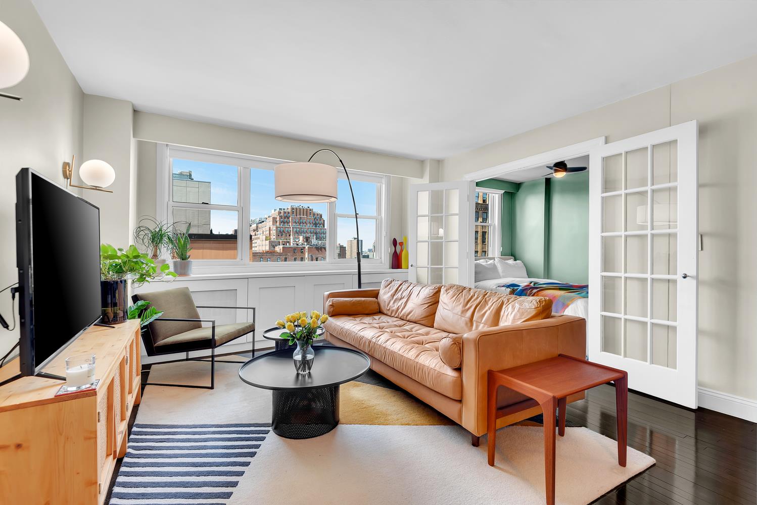 77 7th Avenue, Unit 14L Manhattan, NY 10011 - Photo 1 of 10 a living room with furniture and a flat screen tv