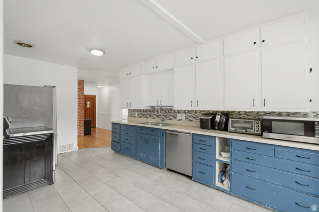707 East 150 South Provo, UT 84606 - Photo 11 of 31 Kitchen featuring extensive white upper cabinetry, blue lower cabinetry with black hardware, a light-toned countertop, and a mosaic tile backsplash