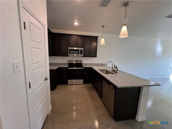 a kitchen with stainless steel appliances granite countertop a sink a stove and a refrigerator