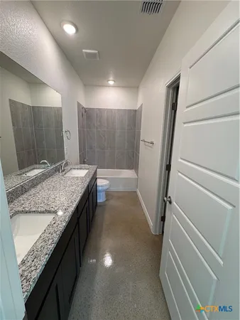 a bathroom with a granite countertop sink a mirror and a bathtub