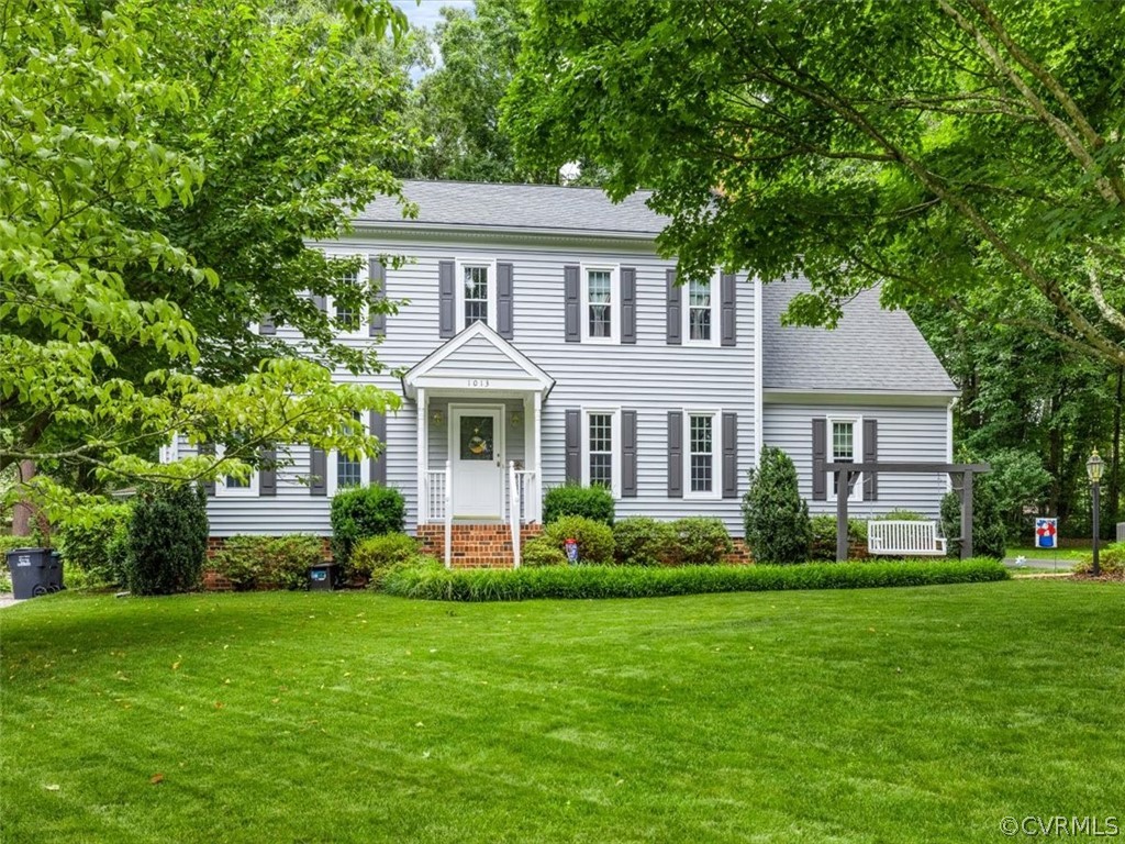 a front view of a house with a garden and trees