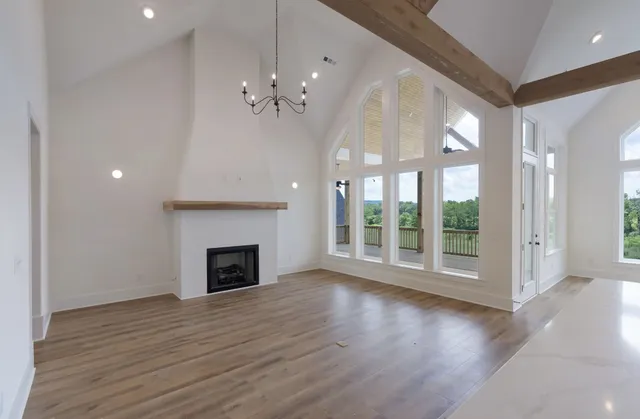 an empty room with wooden floor fireplace and windows