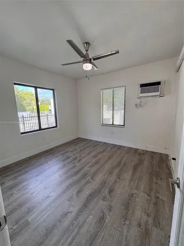 a view of an empty room with a window and wooden floor