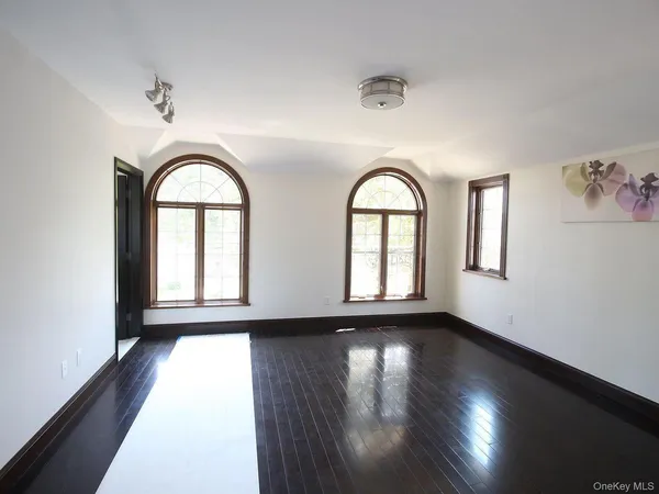 a view of an empty room with wooden floor and window