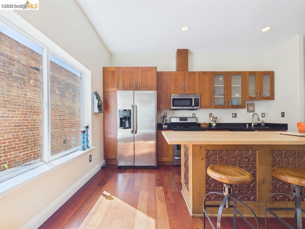 1488 14th Street, Unit A Oakland, CA 94607 - Photo 15 of 36 a kitchen with stainless steel appliances a refrigerator a stove a sink dishwasher and white cabinets with wooden floor