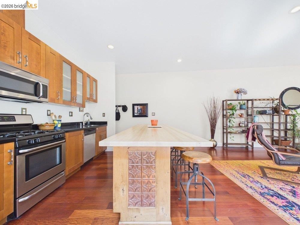 1488 14th Street, Unit A Oakland, CA 94607 - Photo 16 of 36 a kitchen with stainless steel appliances granite countertop a stove top oven a dining table and chairs with wooden floor