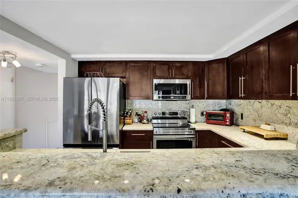 a kitchen with stainless steel appliances granite countertop a sink and a refrigerator
