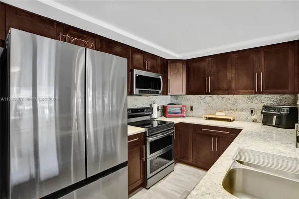 a kitchen with stainless steel appliances kitchen island granite countertop a refrigerator and a stove top oven