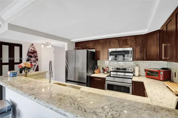 a kitchen with stainless steel appliances granite countertop a sink refrigerator and cabinets