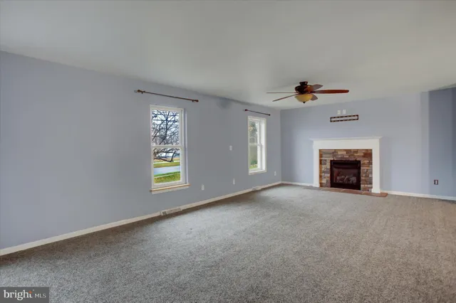 a view of an empty room with window and fireplace