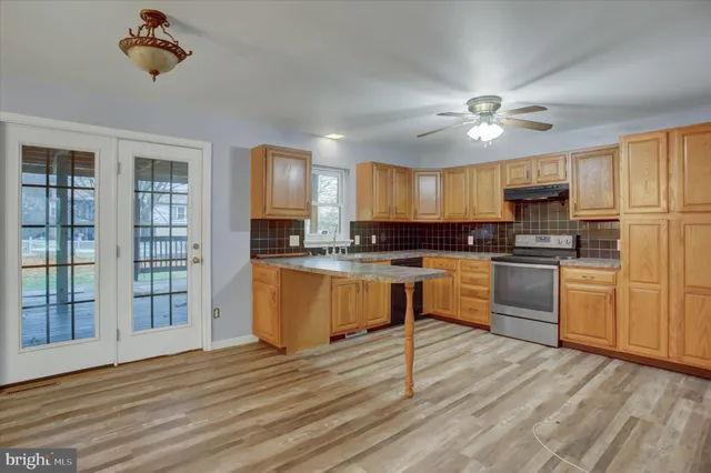 a kitchen with granite countertop wooden floors stainless steel appliances and window