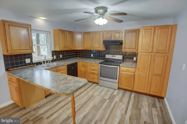 a kitchen with stainless steel appliances granite countertop a sink a stove counter space and cabinets