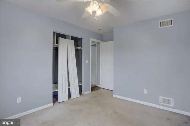 an empty room with a ceiling fan and window
