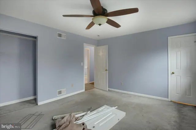 an empty room with a ceiling fan and carpet