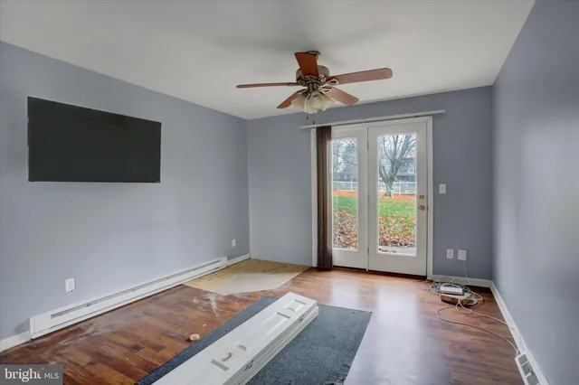 a view of empty room with wooden floor and fan