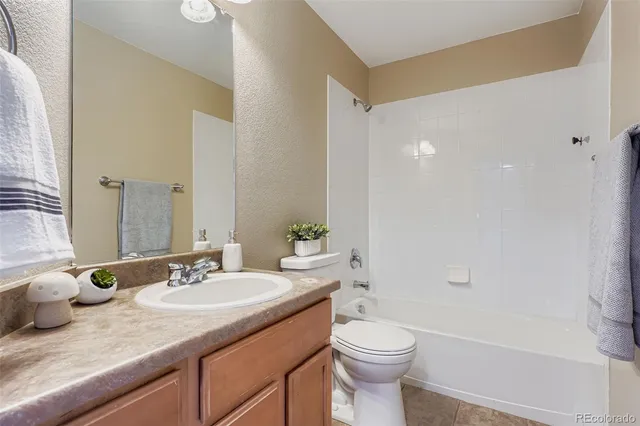 a bathroom with a granite countertop sink a toilet and shower