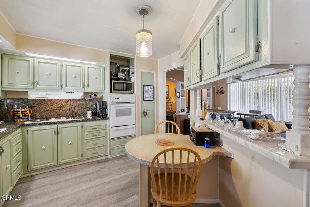 1550 Rory Lane, Unit 82 Simi Valley, CA 93063 - Photo 13 of 27 a kitchen with stainless steel appliances granite countertop a stove a sink dishwasher and white cabinets with wooden floor