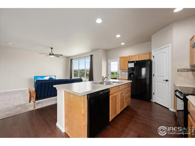 a kitchen with stainless steel appliances kitchen island granite countertop a stove top oven a sink a refrigerator and white cabinets with wooden floor