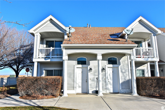 View of front of home featuring a balcony and a shingled roof