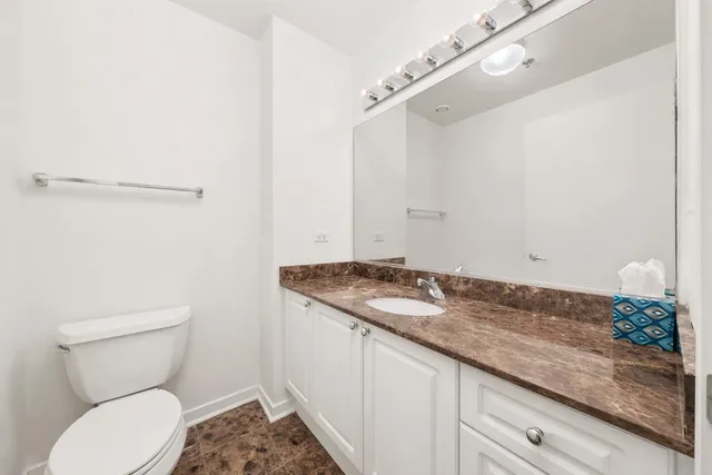 a bathroom with a granite countertop sink a toilet and a mirror