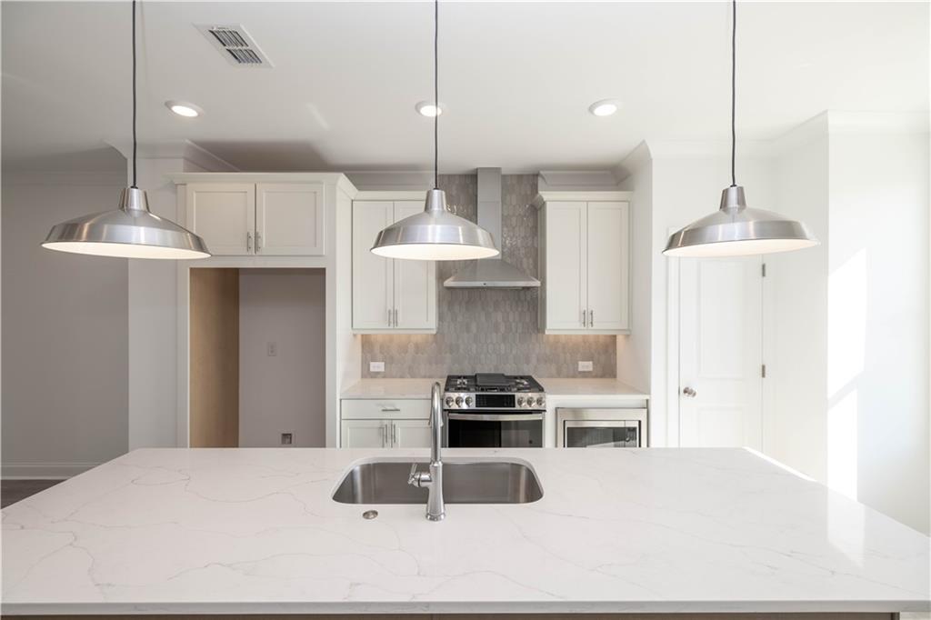 4223 Millcroft Place, Unit 211 Buford, GA 30518 - Photo 14 of 47 a kitchen with stainless steel appliances kitchen island granite countertop a stove a refrigerator a sink a counter and chairs