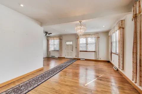 a view of an empty room with window and wooden floor