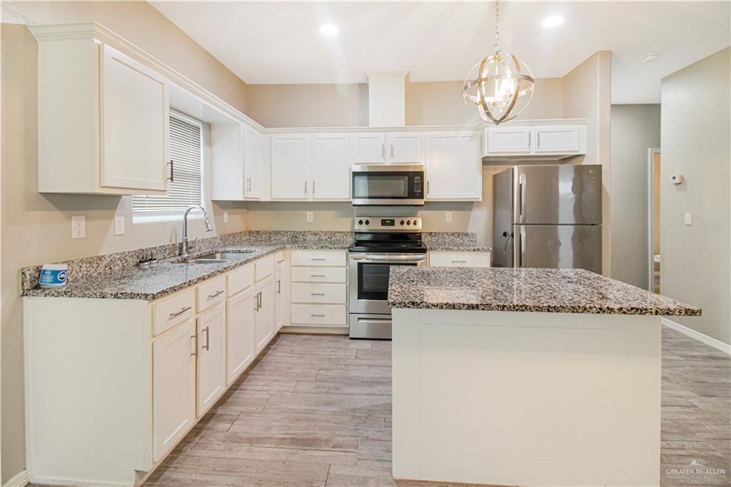 1817 Stauffer Street, Unit 3 Weslaco, TX 78596 - Photo 2 of 12 a kitchen with granite countertop a sink stainless steel appliances and white cabinets