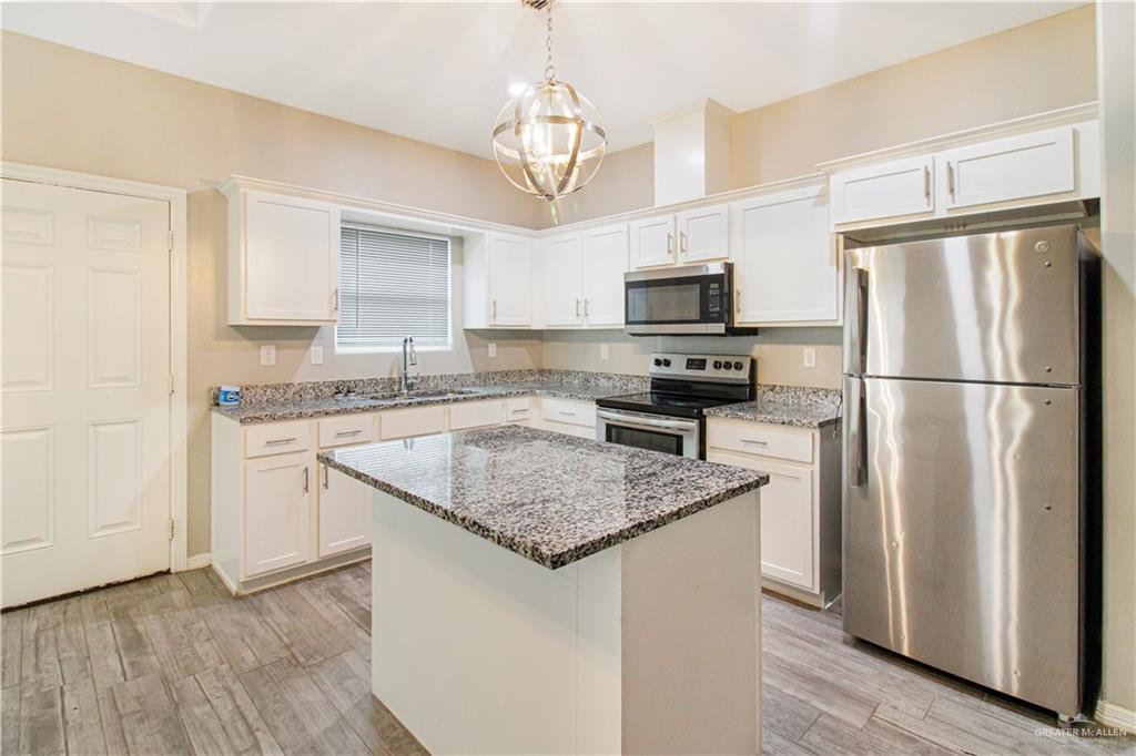 1817 Stauffer Street, Unit 3 Weslaco, TX 78596 - Photo 4 of 12 a kitchen with stainless steel appliances granite countertop a refrigerator a stove a sink dishwasher a microwave oven with a refrigerator and white cabinets