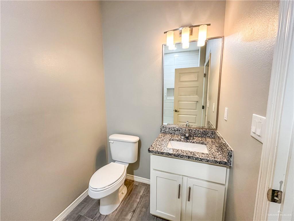 1817 Stauffer Street, Unit 3 Weslaco, TX 78596 - Photo 10 of 12 a bathroom with a granite countertop toilet a sink and a mirror