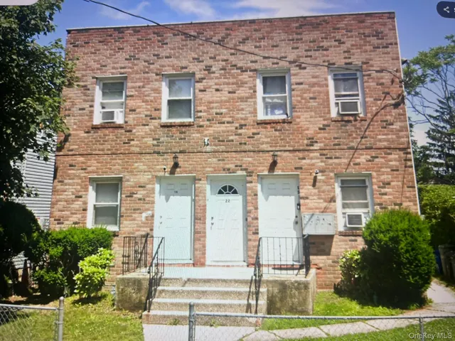 front view of a brick house with a yard and potted plants
