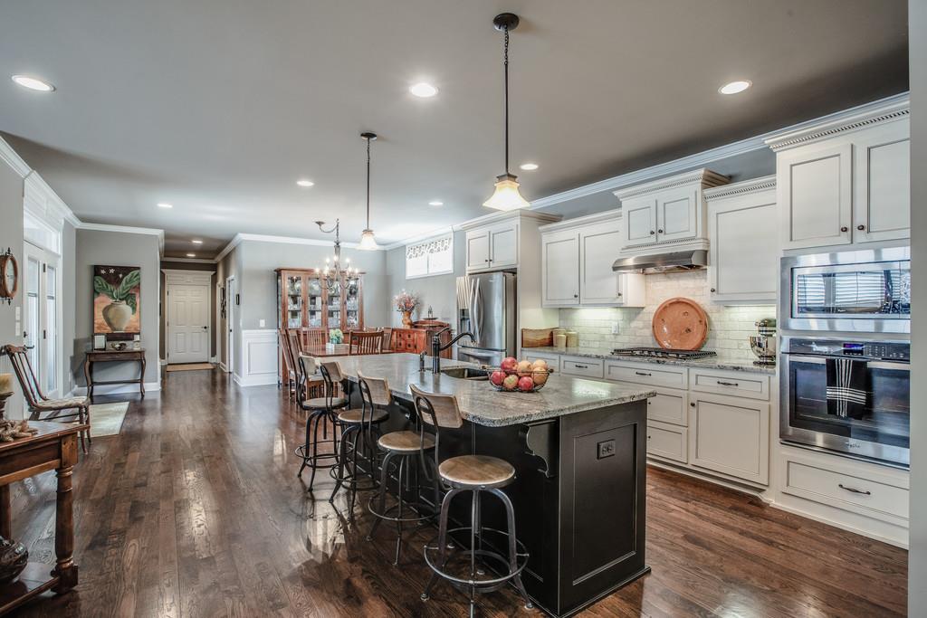 4128 Turnberry Road Spring Hill, TN 37174 - Photo 12 of 30 a kitchen with stainless steel appliances granite countertop a stove top oven a refrigerator a sink and a dining table with wooden floor