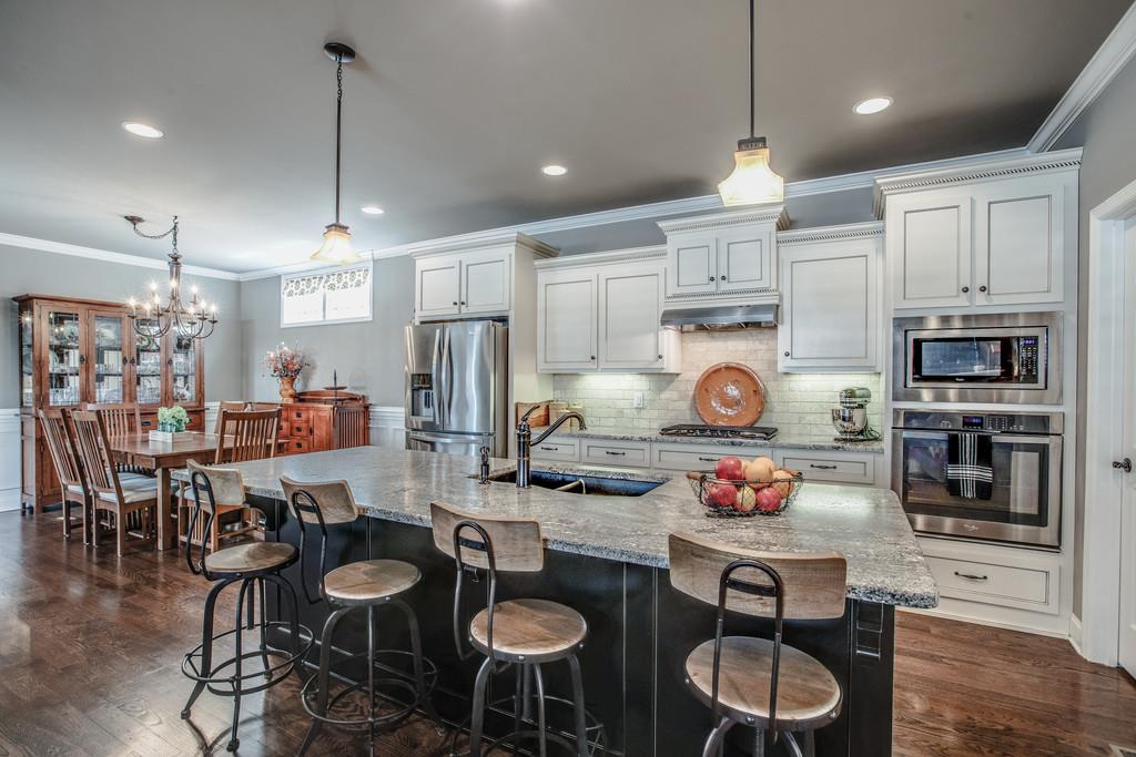 4128 Turnberry Road Spring Hill, TN 37174 - Photo 13 of 30 a kitchen with stainless steel appliances granite countertop a stove a kitchen island a dining table and chairs with wooden floor