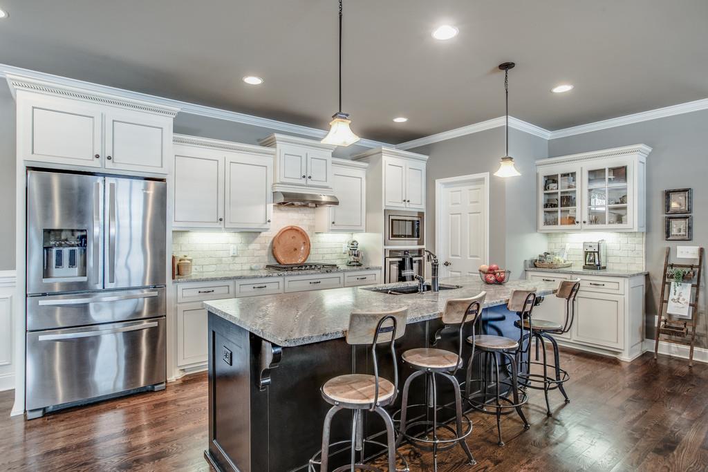 4128 Turnberry Road Spring Hill, TN 37174 - Photo 14 of 30 a kitchen with granite countertop a table chairs stove microwave and refrigerator