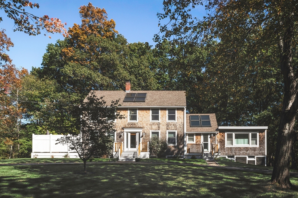 a front view of a house with a garden and trees