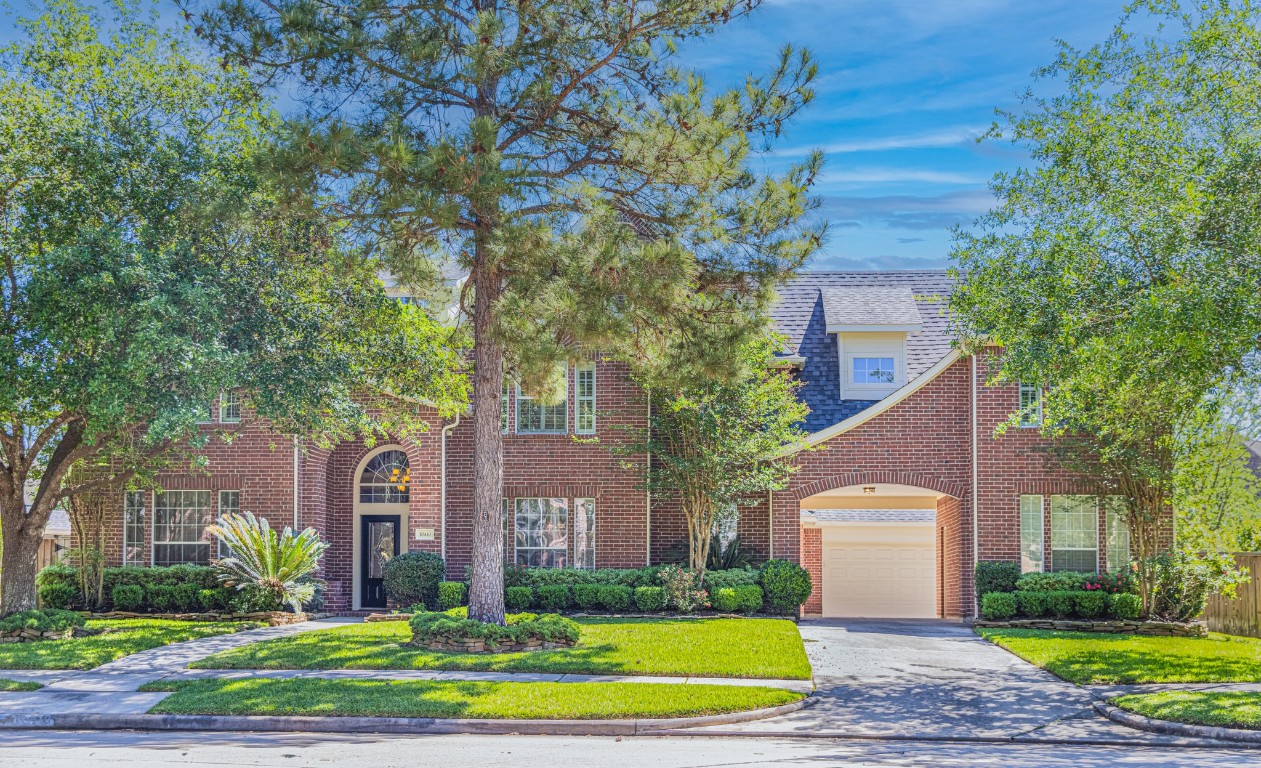 a front view of a house with a yard and trees