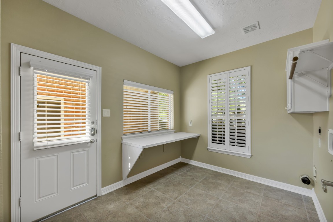 10410 Kilbride Way Court Spring, TX 77379 - Photo 39 of 49 1st floor laundry room with cabinetry, a folding counter and a door exiting to the driveway on the side.