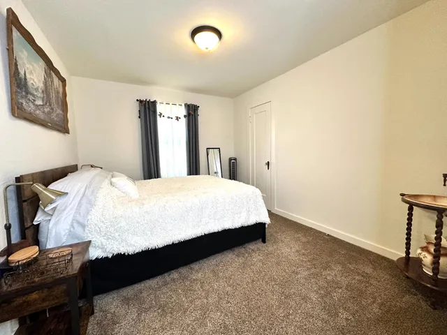 a large bed sitting in a bedroom next to a window with pc on the table
