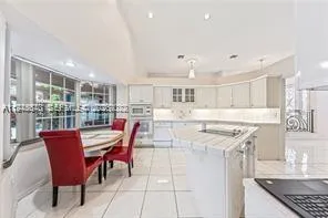 a kitchen with stainless steel appliances kitchen island granite countertop a table chairs and a refrigerator