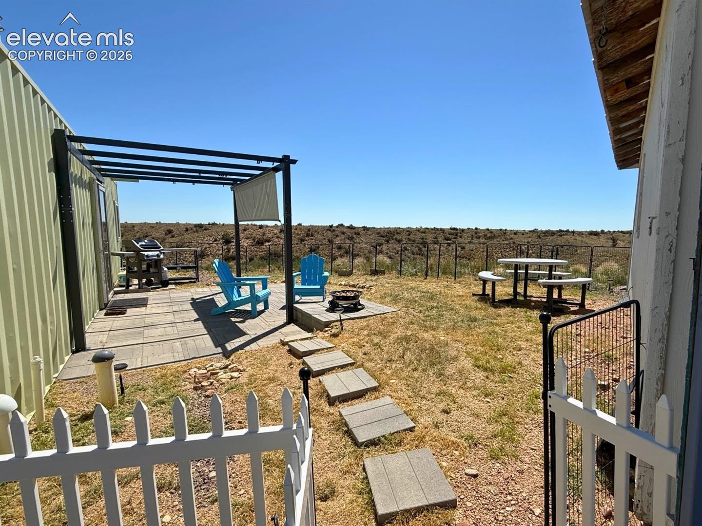 Turnkey 1 Bed - 1 Bath with Outdoor living space featuring a pergola-covered patio, paved stepping stones, and a fenced perimeter.