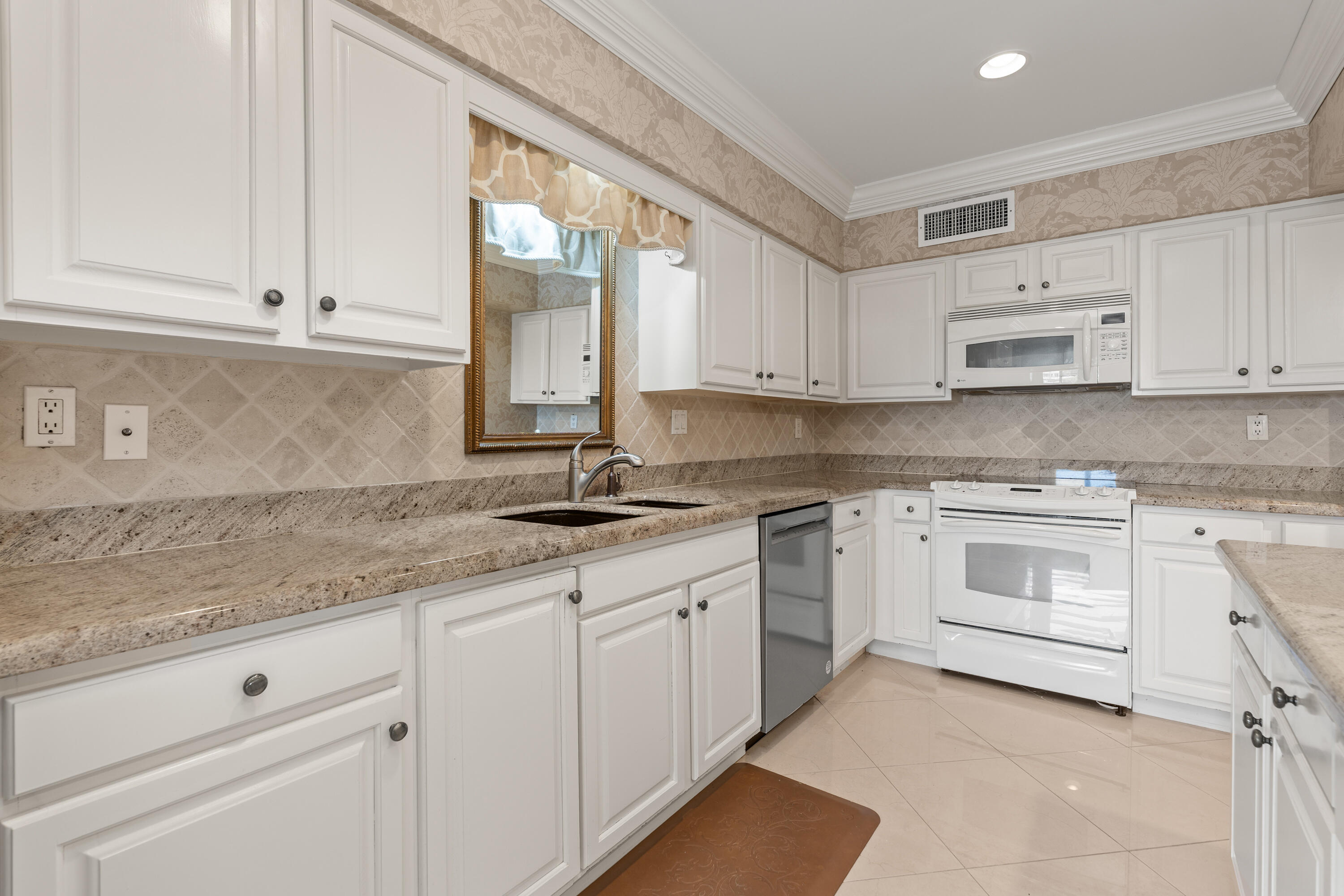 16940 Bay Street, Unit N504 Jupiter, FL 33477 - Photo 21 of 33 a kitchen with granite countertop white cabinets and white appliances