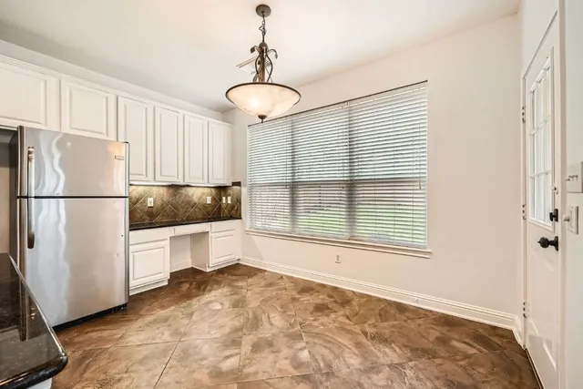 a kitchen with a refrigerator and white cabinets