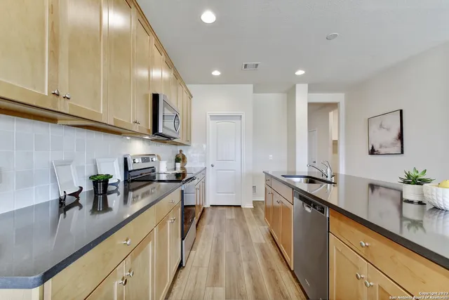 a kitchen with stainless steel appliances a sink a stove top oven a counter space and cabinets